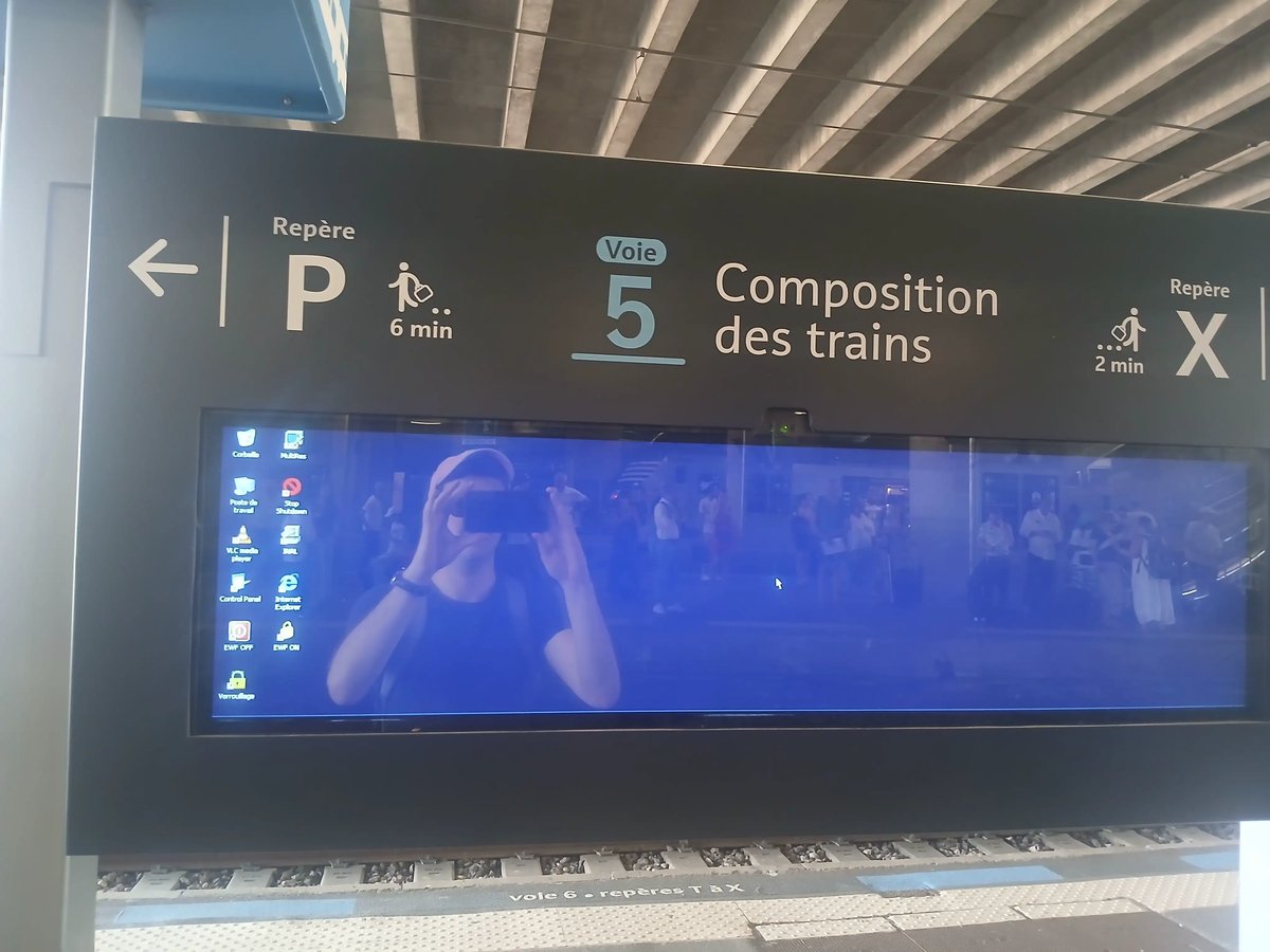 Un écran sur un quai de gare montrant un bureau Windows