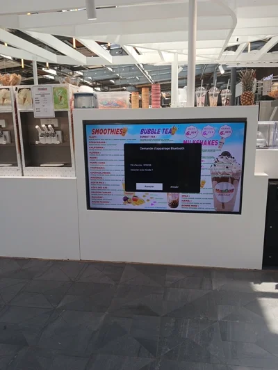 Un écran montrant le menu d'une boutique de jus de fruits avec un menu d'appairage bluetooth par-dessus