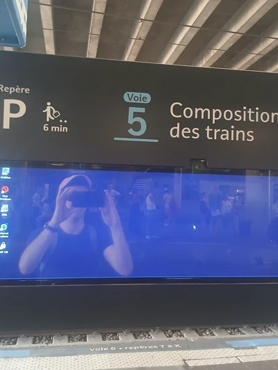 Un écran sur un quai de gare montrant un bureau Windows