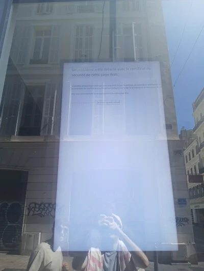 Un écran derrière une vitrine montrant une alerte de sécurité dans un navigateur